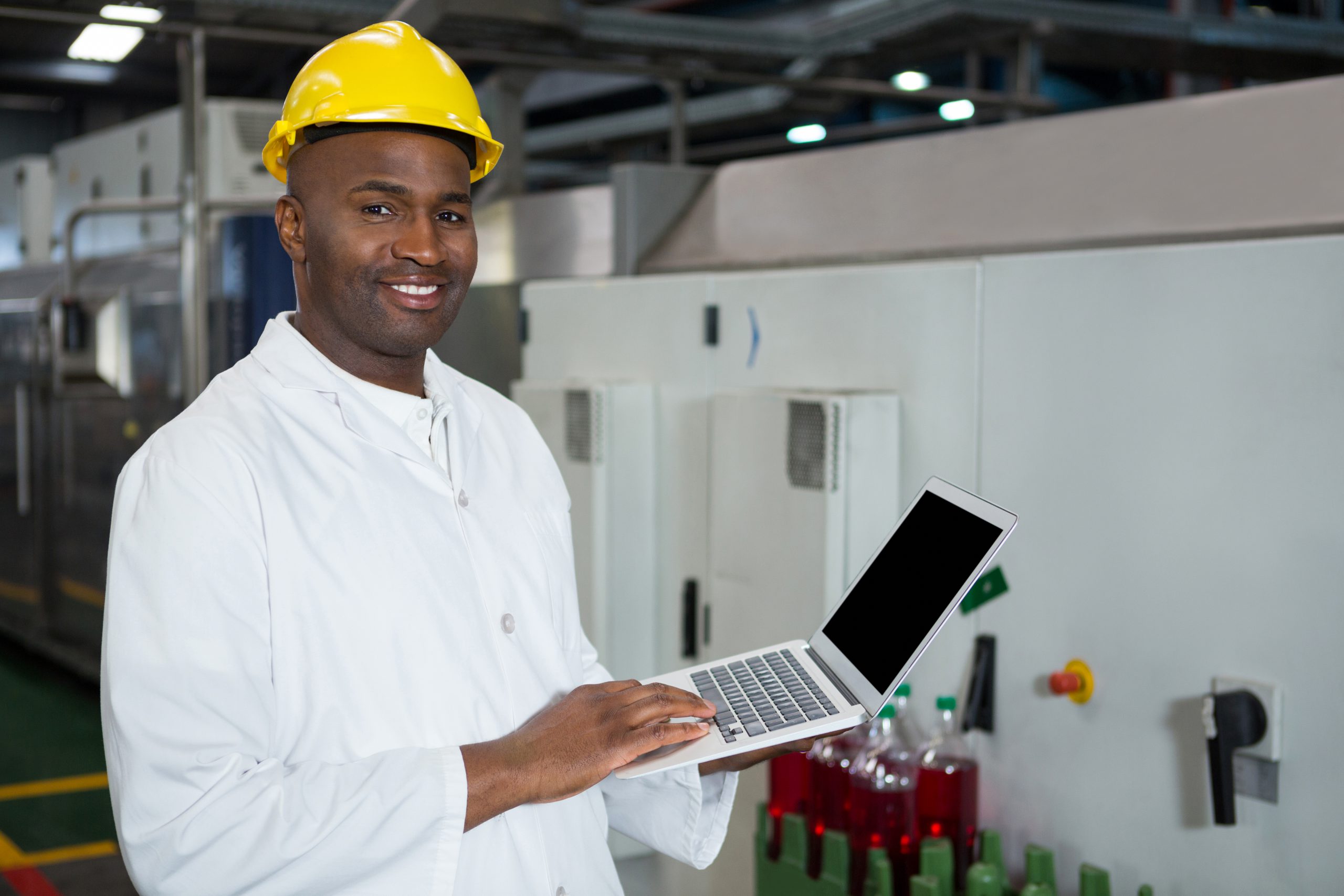 confident male worker using laptop in juice factory